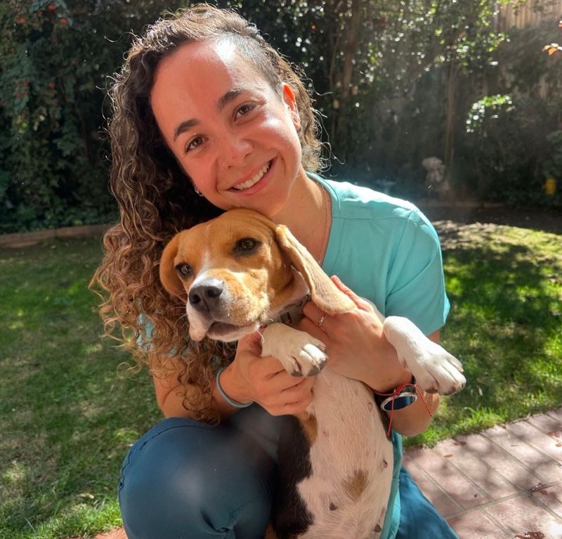 La Dra. Luna Fuentes sonriendo mientras sostiene a un beagle durante una visita a domicilio